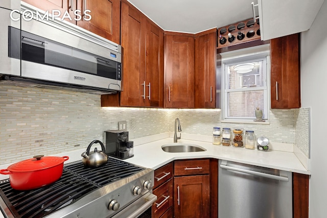 kitchen with backsplash, stainless steel appliances, light countertops, and a sink