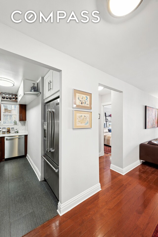 kitchen with backsplash, white cabinets, hardwood / wood-style floors, and appliances with stainless steel finishes