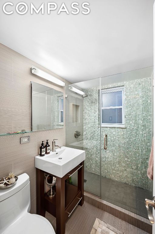 bathroom featuring toilet, tile patterned flooring, a shower with shower door, and sink