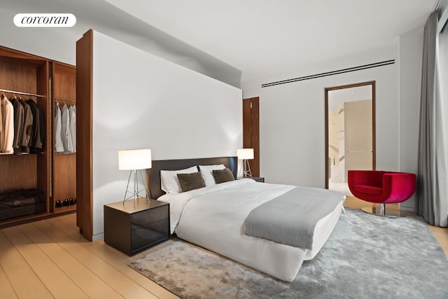 bedroom featuring light wood-type flooring, a closet, and ensuite bath