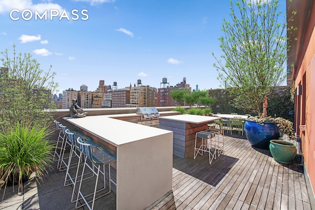 wooden deck with area for grilling, a view of city, and outdoor wet bar