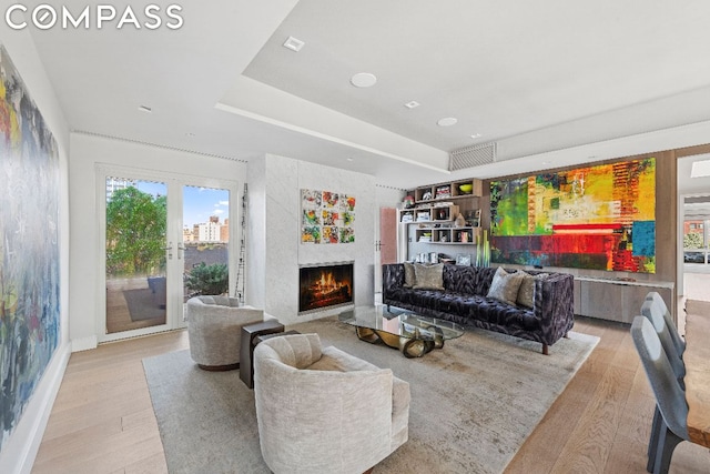 living room featuring french doors, a raised ceiling, and light hardwood / wood-style flooring