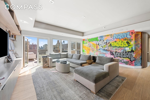 living room featuring a tray ceiling, a view of city, and light wood-style floors