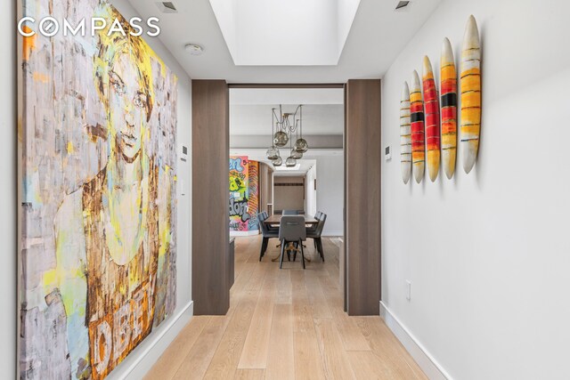 corridor with baseboards and light wood-style floors