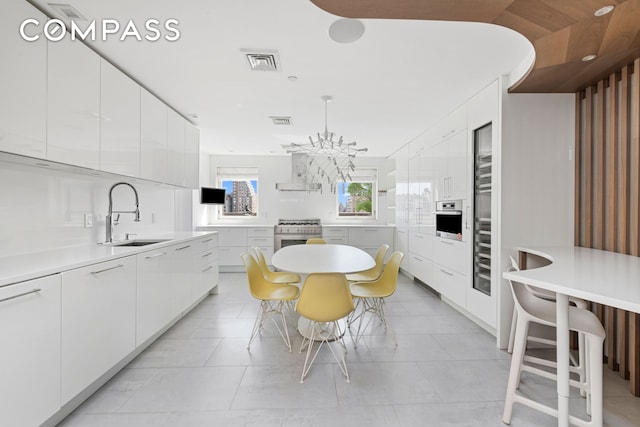 kitchen with oven, visible vents, modern cabinets, a sink, and range with gas stovetop