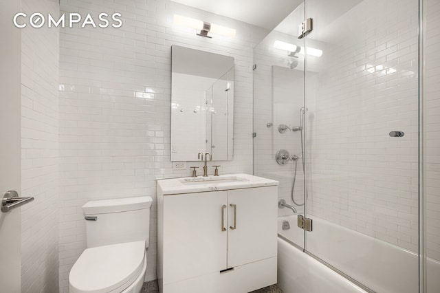 full bath with toilet, combined bath / shower with glass door, vanity, and tile walls