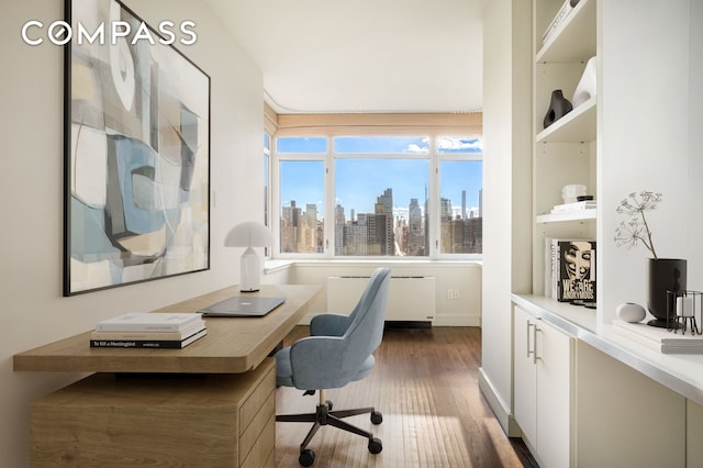 office space featuring dark wood-type flooring, a city view, and radiator heating unit