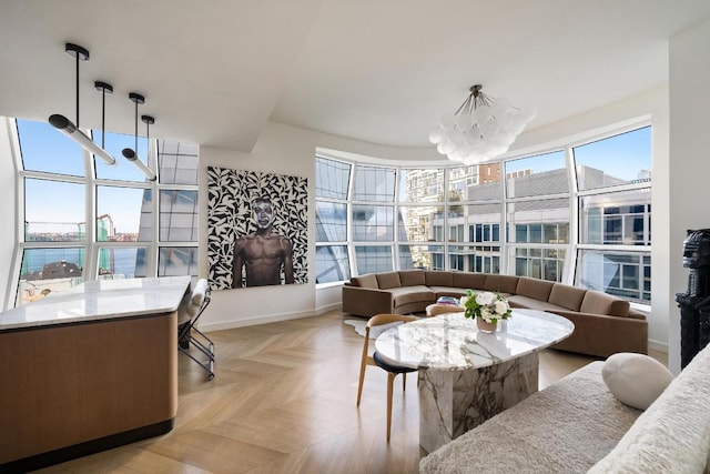 living room featuring an inviting chandelier, a healthy amount of sunlight, and light parquet floors