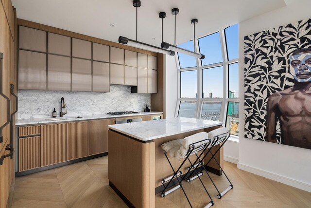 kitchen featuring decorative light fixtures, sink, backsplash, a center island, and light parquet flooring