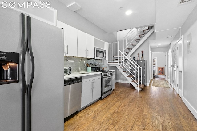 kitchen featuring white cabinetry, stainless steel appliances, tasteful backsplash, light wood-type flooring, and sink