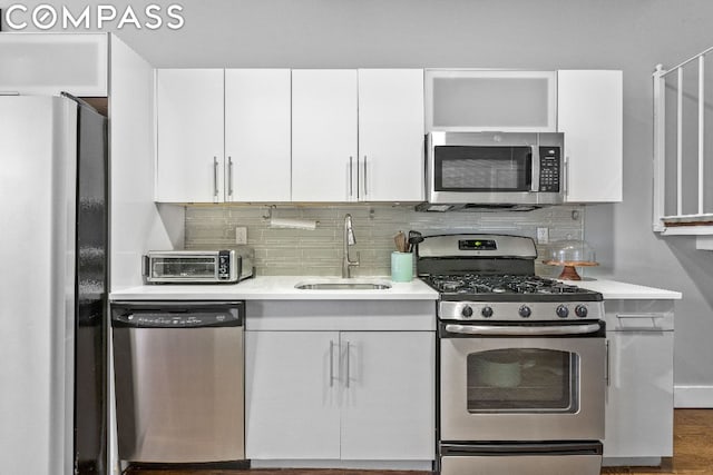 kitchen featuring stainless steel appliances, backsplash, white cabinets, and sink