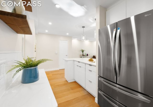 kitchen featuring light hardwood / wood-style floors, stainless steel fridge, white cabinetry, and pendant lighting