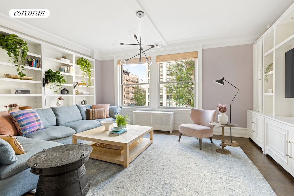 living area with a notable chandelier, dark wood-type flooring, visible vents, and radiator