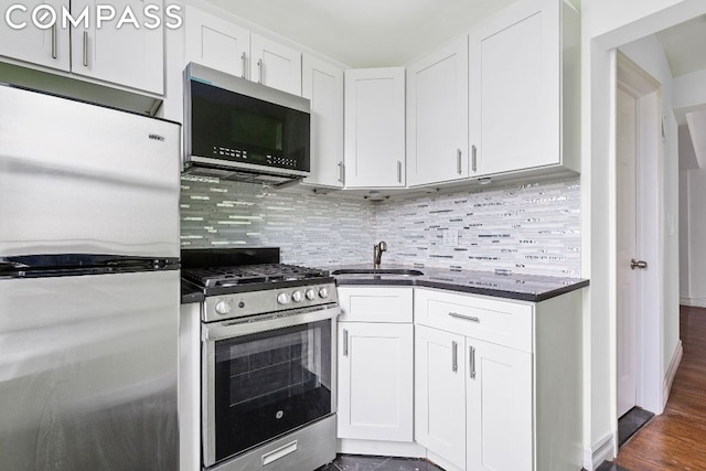 kitchen with white cabinets, decorative backsplash, sink, and stainless steel appliances