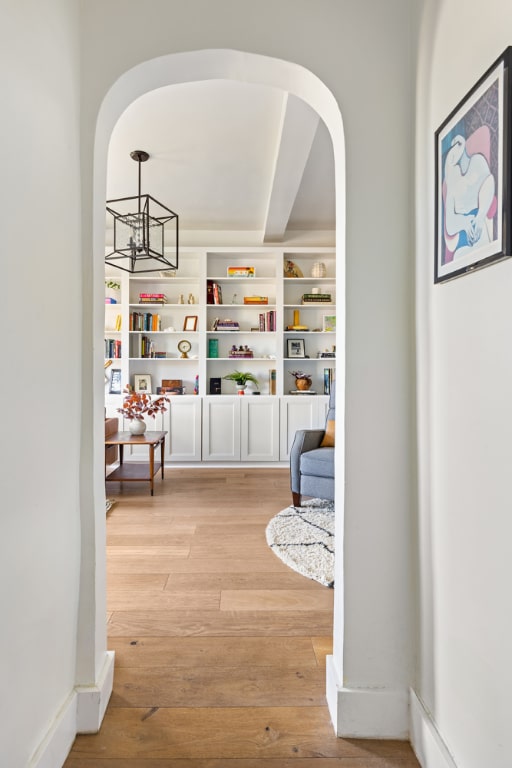 hallway featuring a chandelier, light hardwood / wood-style flooring, and built in shelves