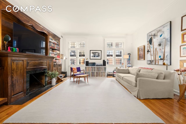 living room with wood finished floors, a high end fireplace, and crown molding