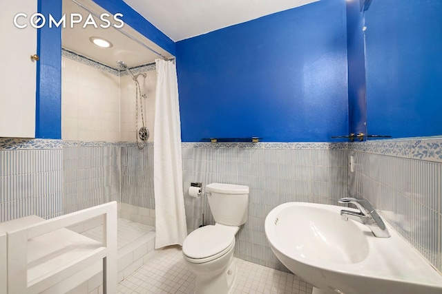 full bathroom with a stall shower, wainscoting, toilet, tile patterned floors, and a sink