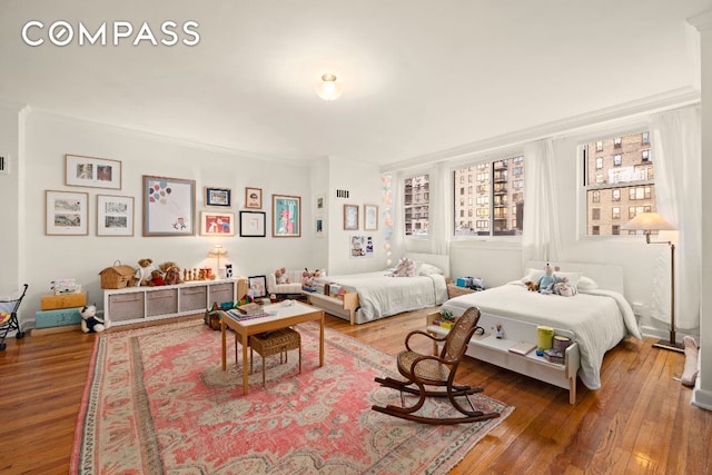 bedroom with wood finished floors and crown molding