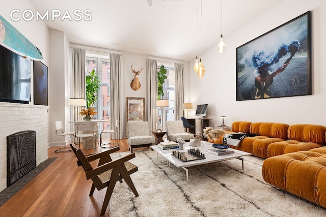 living area featuring light wood-type flooring and a brick fireplace