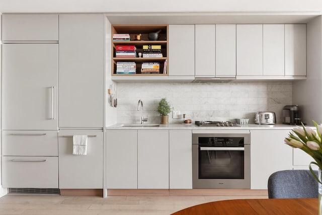 bar featuring tasteful backsplash, appliances with stainless steel finishes, sink, and white cabinets