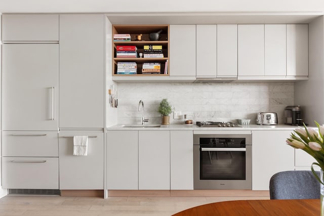 kitchen with light countertops, appliances with stainless steel finishes, white cabinetry, a sink, and modern cabinets