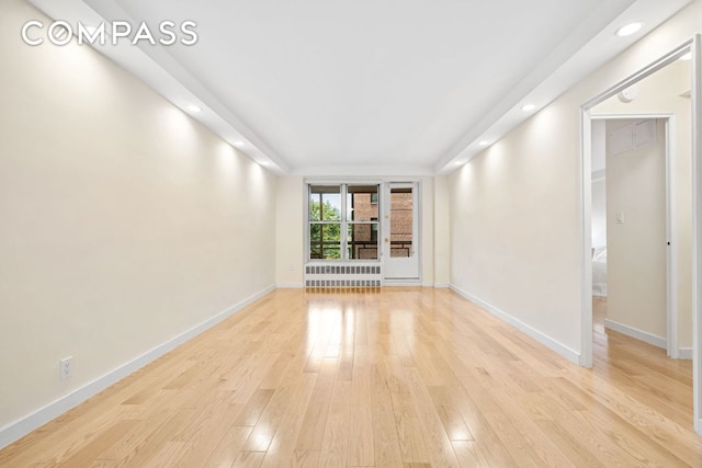 interior space featuring radiator heating unit and light hardwood / wood-style flooring