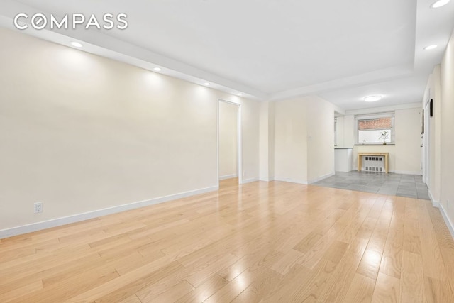 unfurnished living room featuring radiator heating unit and light hardwood / wood-style flooring