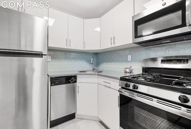 kitchen with white cabinetry, stainless steel appliances, decorative backsplash, sink, and light tile patterned flooring