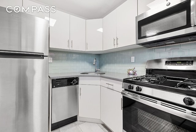 kitchen with sink, white cabinetry, appliances with stainless steel finishes, light stone countertops, and decorative backsplash