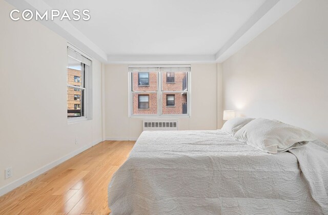 bedroom featuring radiator and hardwood / wood-style flooring