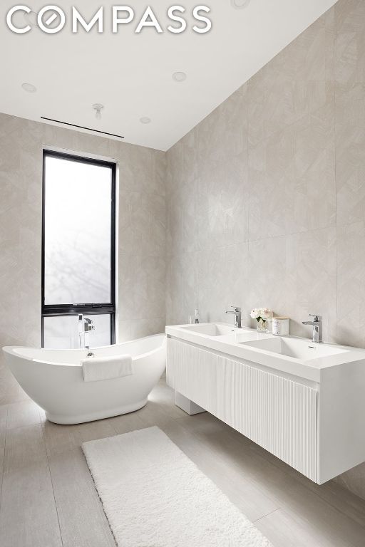 bathroom featuring tile walls, vanity, a bathing tub, and tile patterned flooring