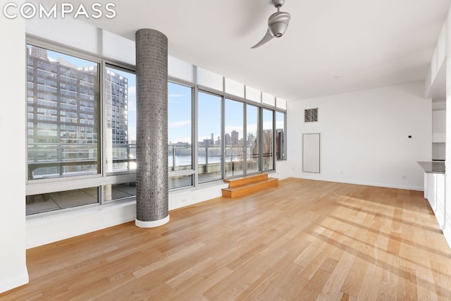 unfurnished living room featuring light hardwood / wood-style flooring, ceiling fan, and a water view