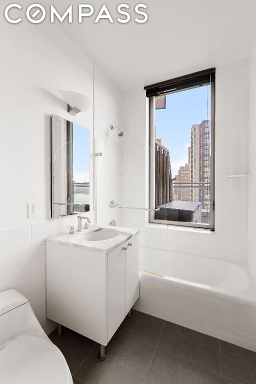 full bathroom with tile patterned floors, toilet, tile walls, vanity, and tiled shower / bath combo