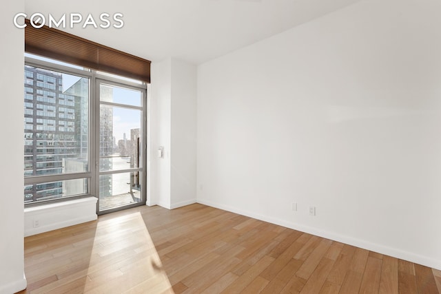 spare room with a view of city, baseboards, and wood finished floors