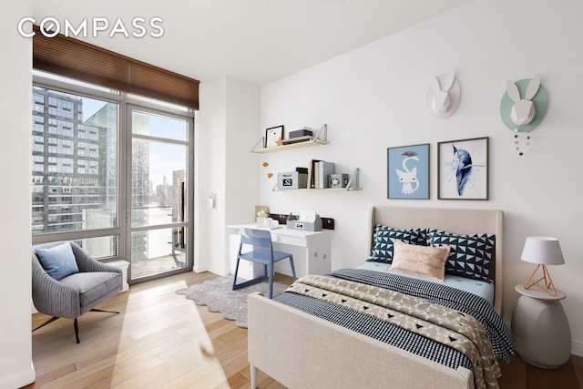 bedroom with a view of city, access to outside, baseboards, and wood finished floors