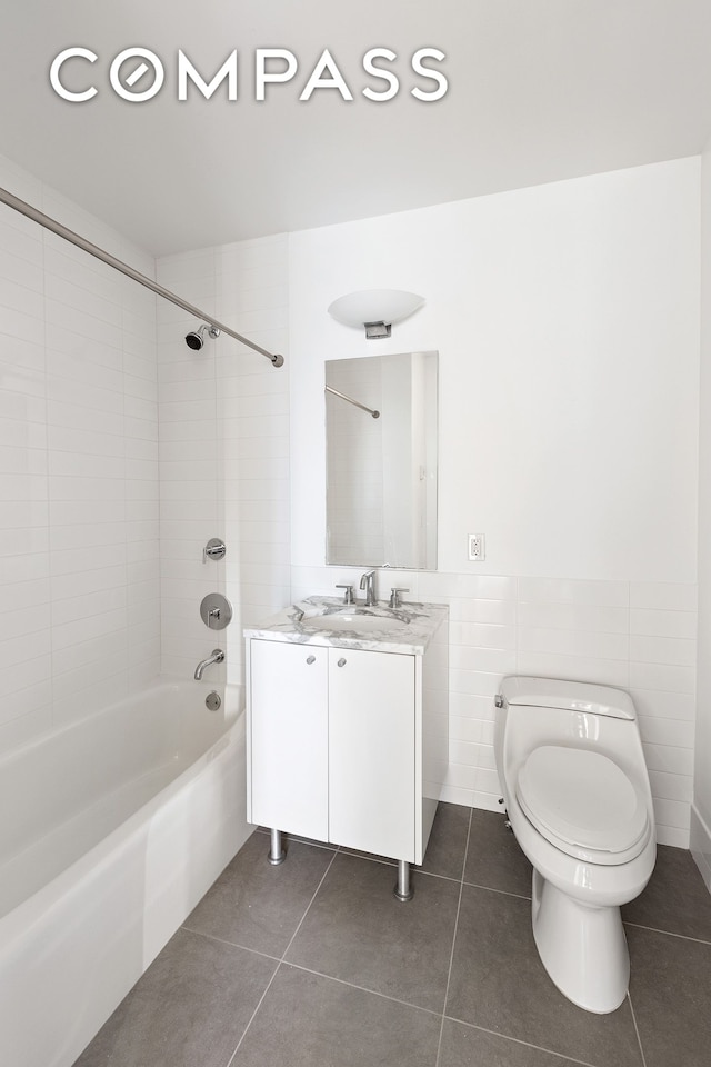 bathroom with toilet, tile patterned flooring, bathtub / shower combination, vanity, and tile walls