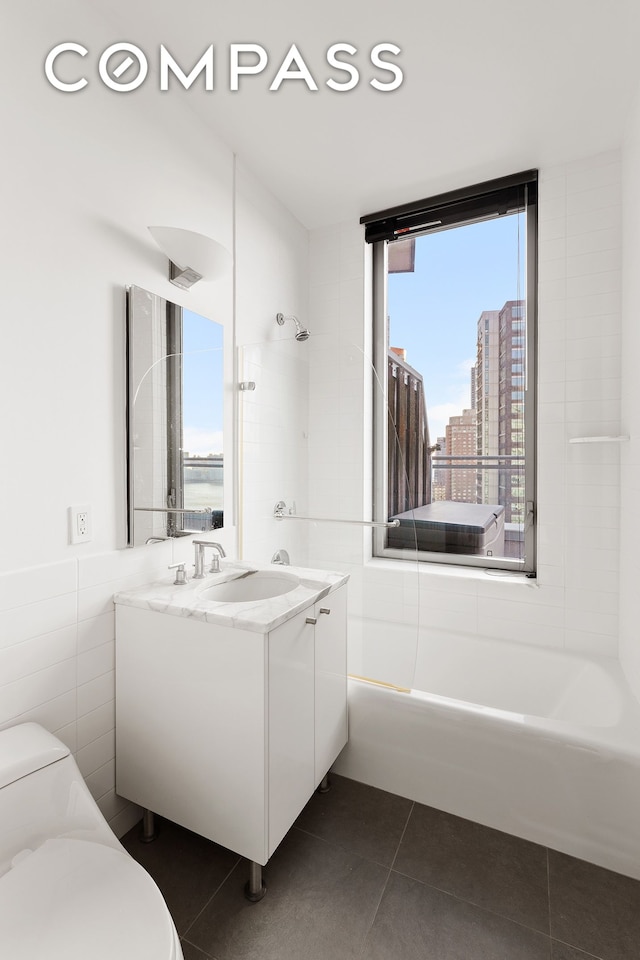 bathroom featuring toilet, tile walls, vanity, shower / bathing tub combination, and tile patterned floors