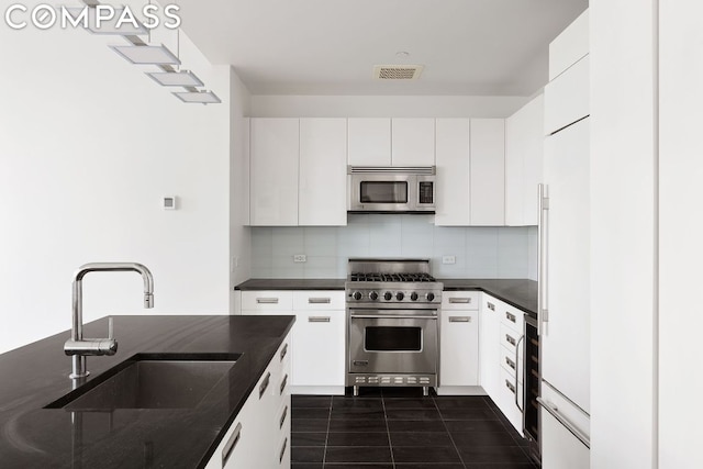 kitchen featuring stainless steel appliances, sink, decorative backsplash, and white cabinets