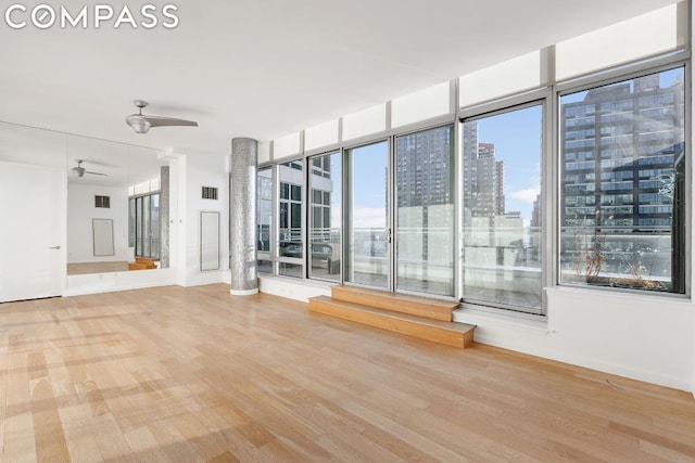 unfurnished room featuring wood-type flooring, a wealth of natural light, and ceiling fan