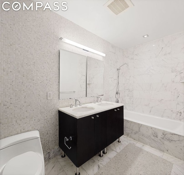 full bathroom featuring tiled shower / bath combo, vanity, tile walls, and toilet