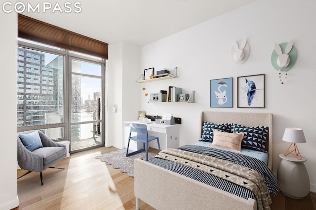 bedroom featuring access to exterior, a wall of windows, and light hardwood / wood-style floors