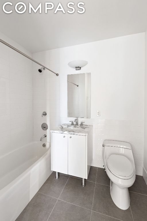 full bathroom featuring tile walls, vanity, tile patterned floors, and tiled shower / bath