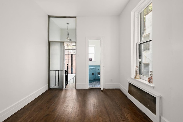 empty room featuring dark wood-type flooring and a chandelier