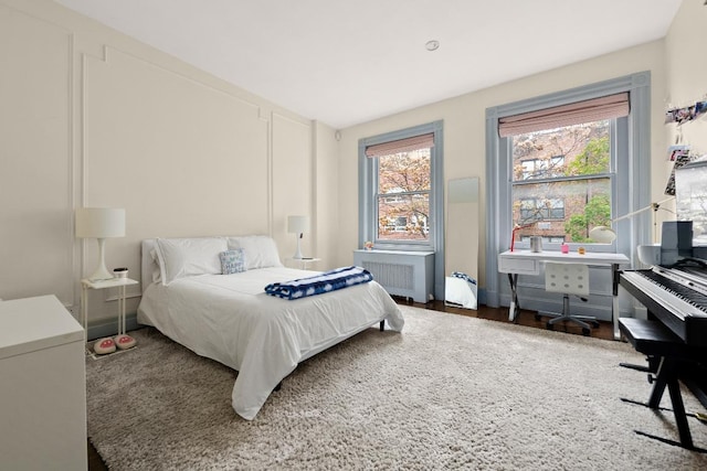 bedroom featuring multiple windows, radiator, and dark wood-type flooring