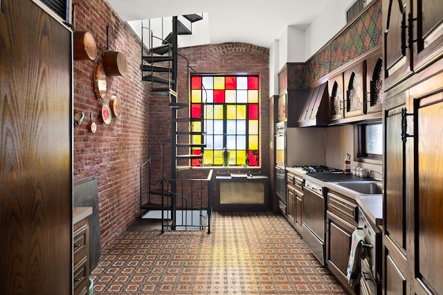51 E 75th St, New York City, NY 10021 - kitchen with stainless steel appliances, a sink, brick wall, vaulted ceiling, and dark brown cabinetry