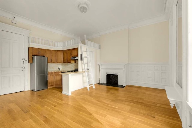 117 W 75th St Unit Twnh, New York City, NY 10023 - kitchen featuring freestanding refrigerator, open floor plan, a fireplace with flush hearth, light countertops, and brown cabinetry