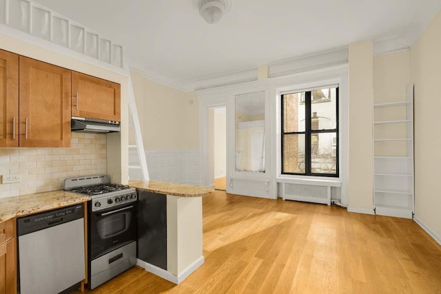 117 W 75th St Unit Twnh, New York City, NY 10023 - kitchen with stainless steel appliances, range hood, brown cabinetry, radiator, and backsplash