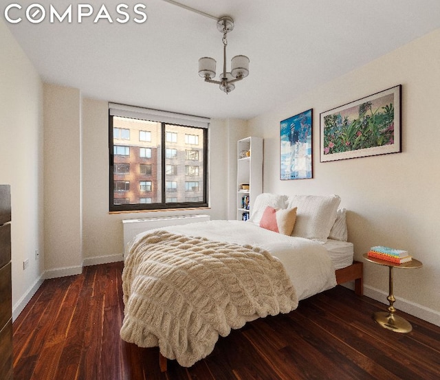 bedroom with dark hardwood / wood-style flooring, a chandelier, and radiator heating unit