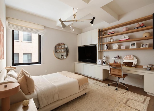 bedroom featuring hardwood / wood-style floors, built in desk, and beam ceiling