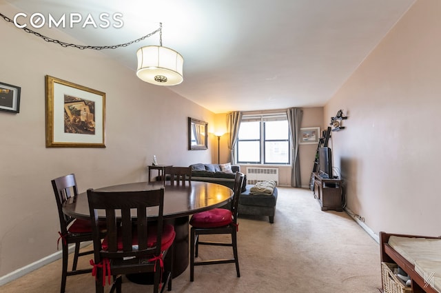 dining area featuring light carpet, radiator heating unit, and baseboards